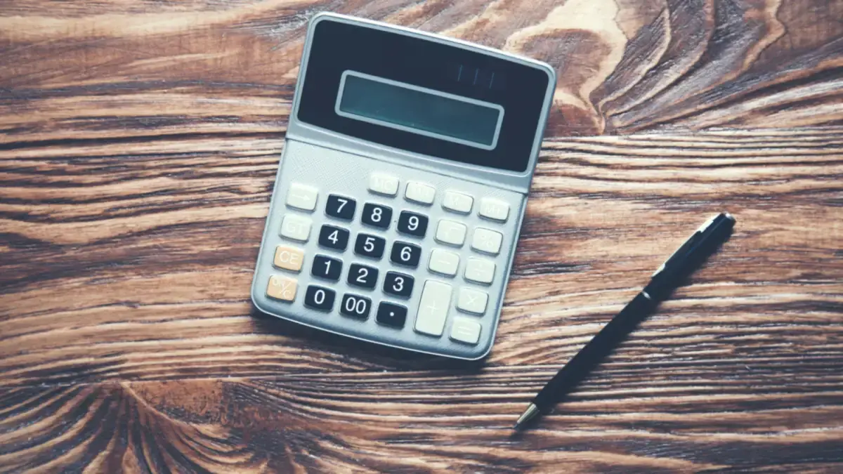 Costs 1 Calculator and pen on a wooden table
